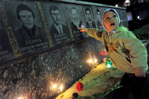 Một cậu bé chỉ vào bức ảnh của bà mình tại tấm bia tưởng niệm nạn nhân trong vụ Chernobyl ở Slavutich, Ukraine. 
